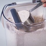Progressive Flour keeper + with view of magnetic, removable leveler leveling off a cup of flour inside the keeper