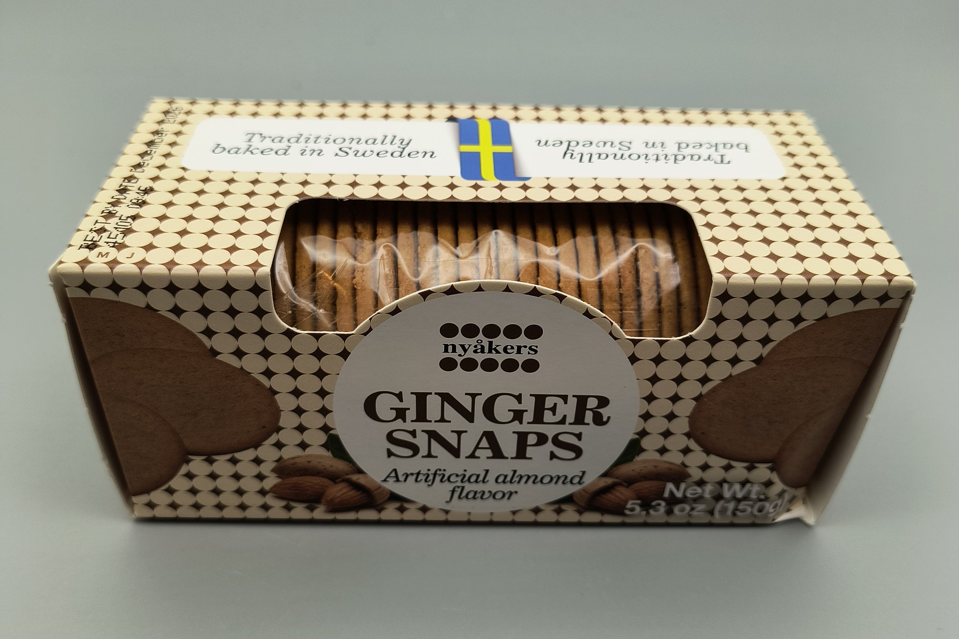 Box of Almond flavored ginger snaps with a clear window showing the cookies inside, on a gray background.