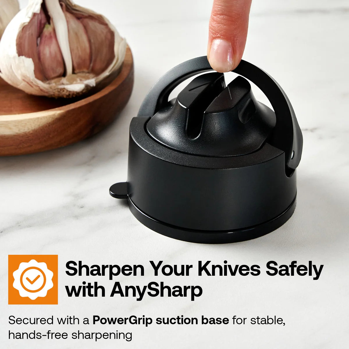 Black knife sharpener on a marble surface with garlic in the background, featuring AnySharp branding.