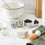 Measuring Cups with ingredients- a bowl, flour, blackberries, eggs and egg shells