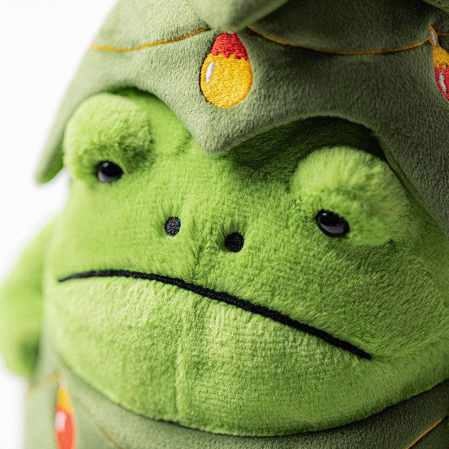 Close-up ofPlush toy frog with a grumpy face dressed as a Christmas tree with lights and a star on a white background