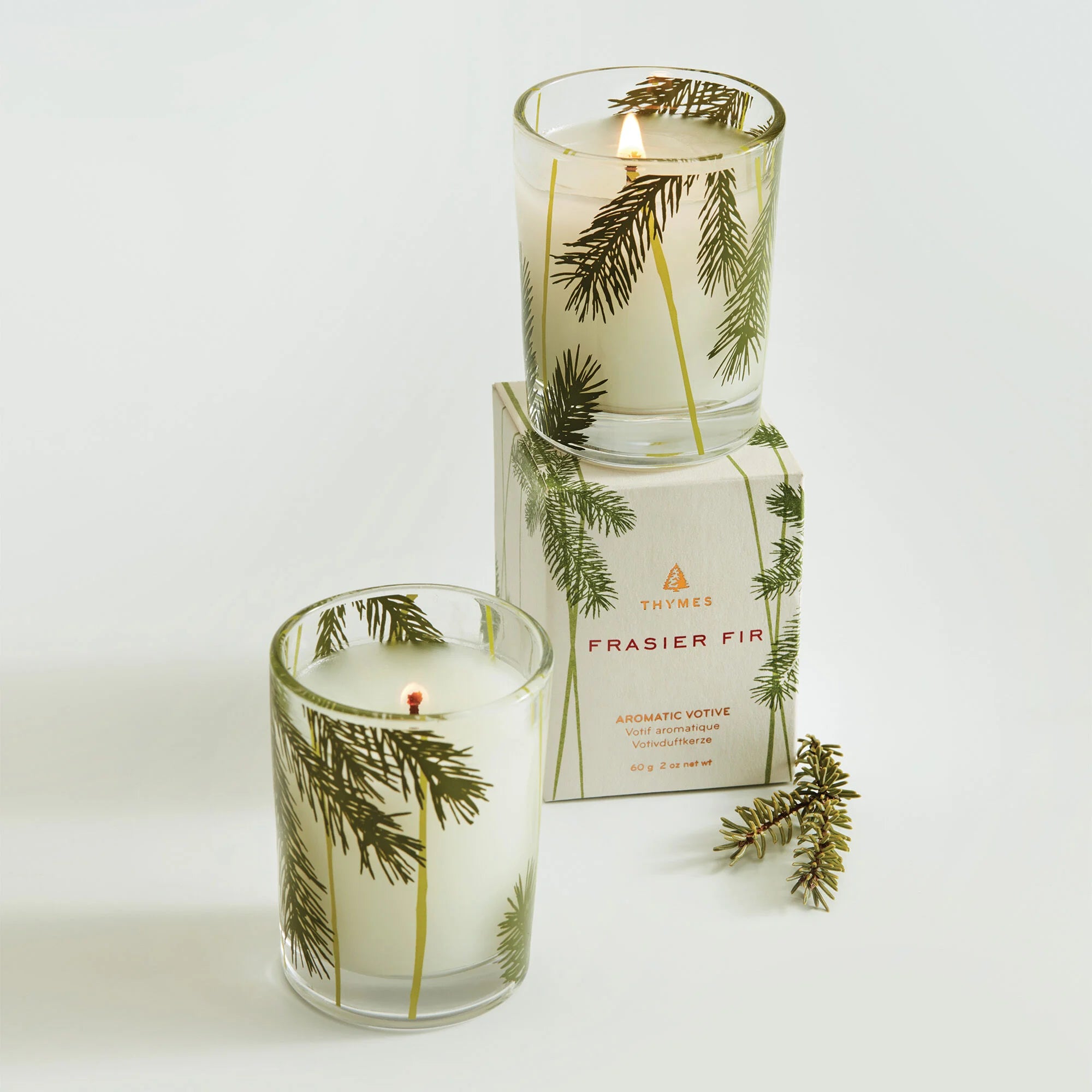 Thymes Frasier Fir Votive Pine Needle Design Candle and packaging stacked on each other