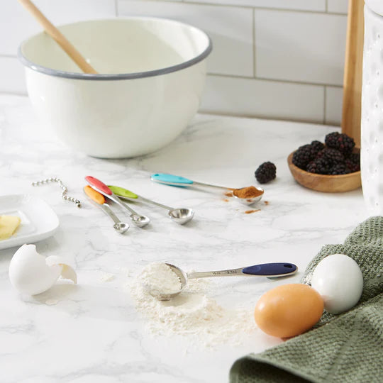 Colorful set of measuring spoons on counter with ingredients