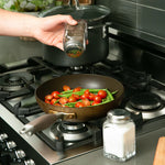 Salt and Pepper spicing on veggies on stove