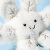 White snowflake plush toy with a smiling face against a light blue background