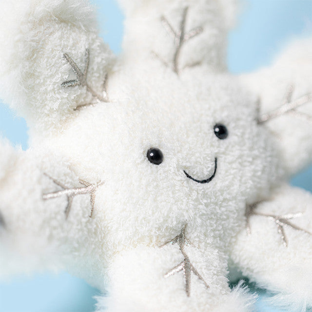 White snowflake plush toy with a smiling face against a light blue background