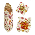 Bees Wrap Assorted 3 Pack (S, M, L) Meadow Magic wrapping a loaf of bread, some cherry tomatoes, and half of an avocado