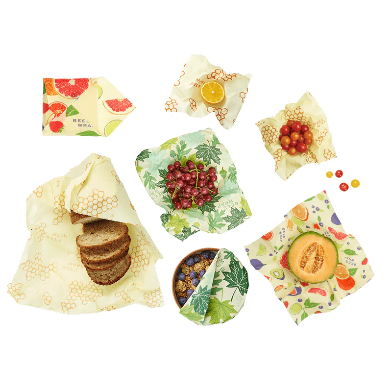 Picture of the Bees Wrap Variety Pack Honeycomb, Clover, Geometric with bread, grapes, bowl, melon half, lemon, and tomatoes.  Showing all the ways you can use the wrap