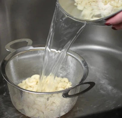 RSVP Wide Rim Mesh Basket filled with pasta being strained with water