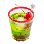 Green cocktail with red sugar rim, cherry, and snowflake garnish on a white background