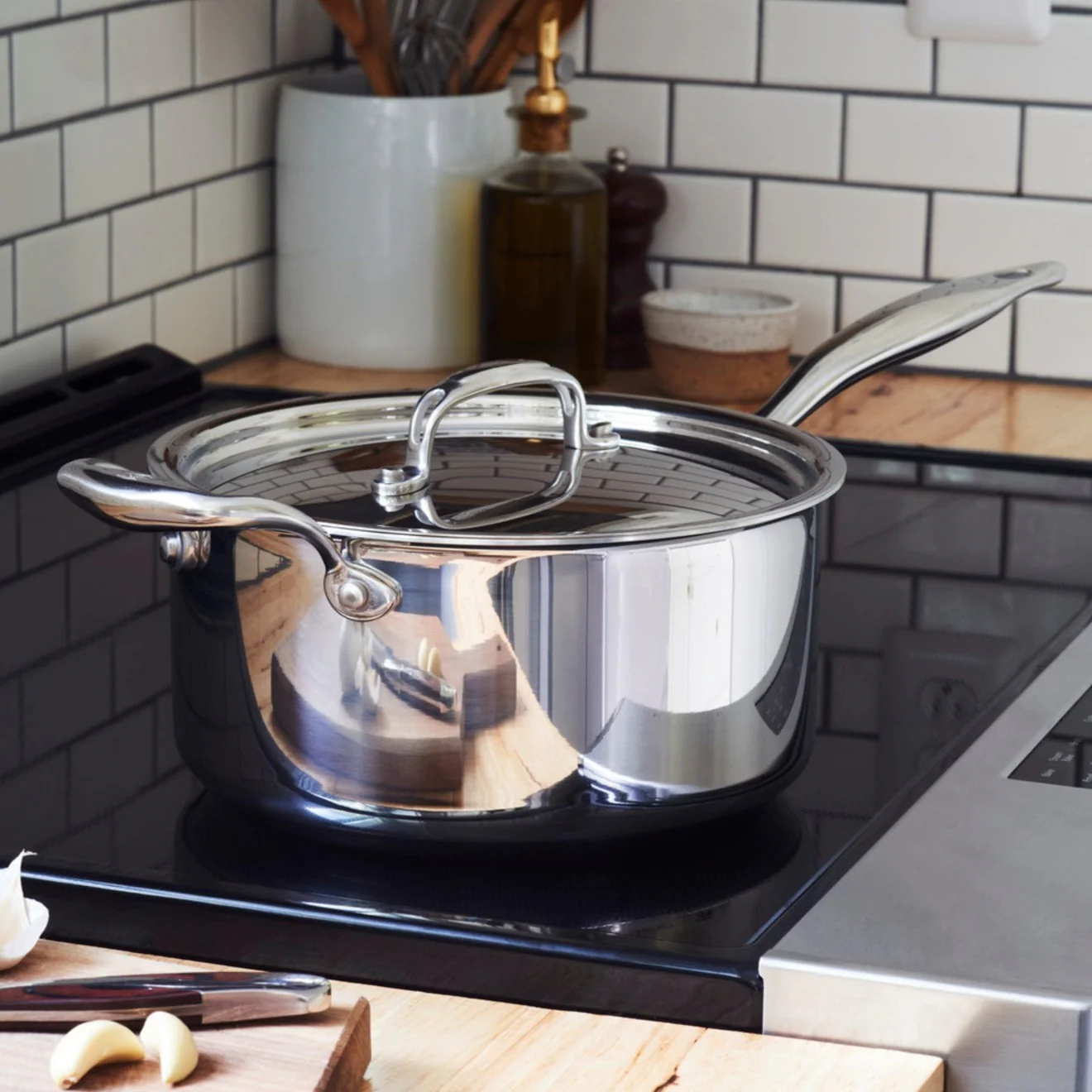 Stainless steel pot on a stove with a kitchen background