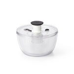 Clear salad spinner with black lid on a white background