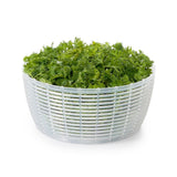 White colander with green leafy vegetables on a white background