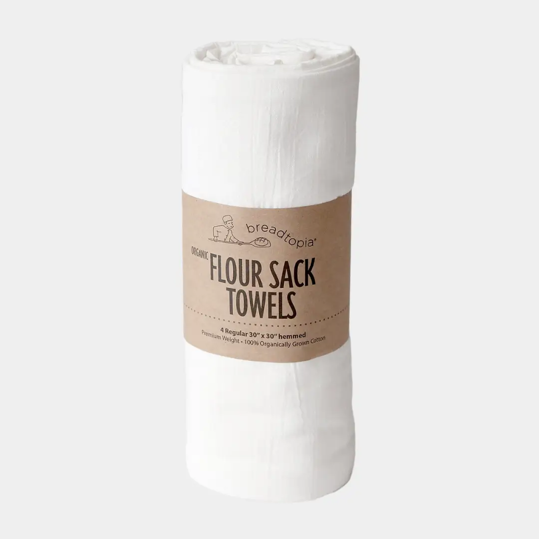 Roll of white flour sack towels with a brown label on a light gray background