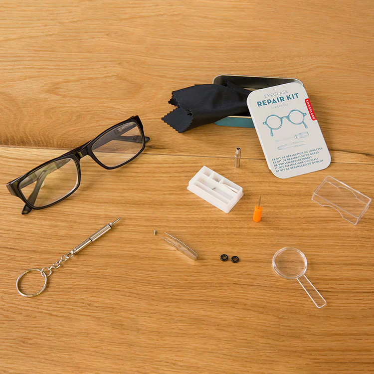Eyeglasses with a repair kit on a wooden surface