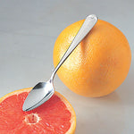 Grapefruit Spoon leaning on a grapefruit half and against a full grapefruit