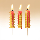 Three honeycomb-shaped candles with pink drips on a beige background